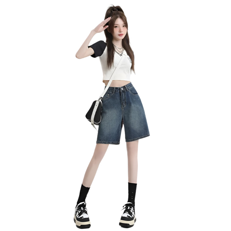 Person wearing a white crop top, blue denim shorts, and black sneakers on a white background